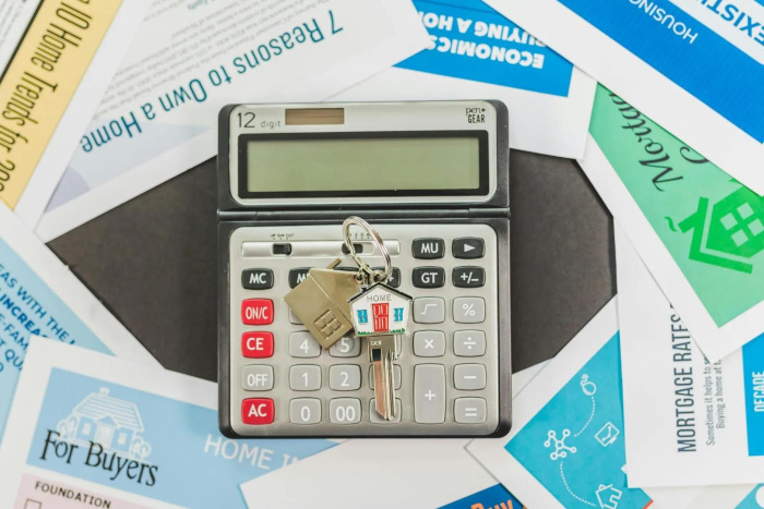 A calculator and mortgage documents on a table - 100% finaning home loans in Houston